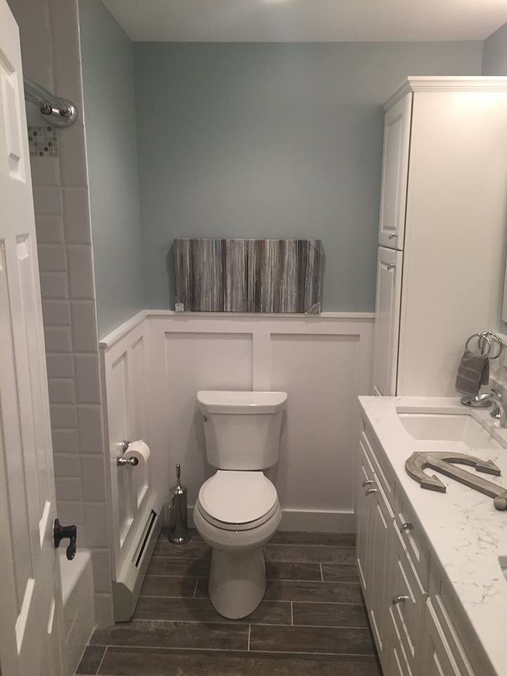 Klassisk inredning av ett mellanstort badrum med dusch, med luckor med upphöjd panel, vita skåp, ett badkar i en alkov, en dusch/badkar-kombination, en toalettstol med separat cisternkåpa, vit kakel, gröna väggar, klinkergolv i porslin, ett undermonterad handfat, bänkskiva i kvarts, grått golv och dusch med duschdraperi