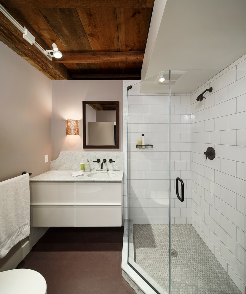 Modern inredning av ett badrum med dusch, med ett undermonterad handfat, vita skåp, en hörndusch, vit kakel och tunnelbanekakel