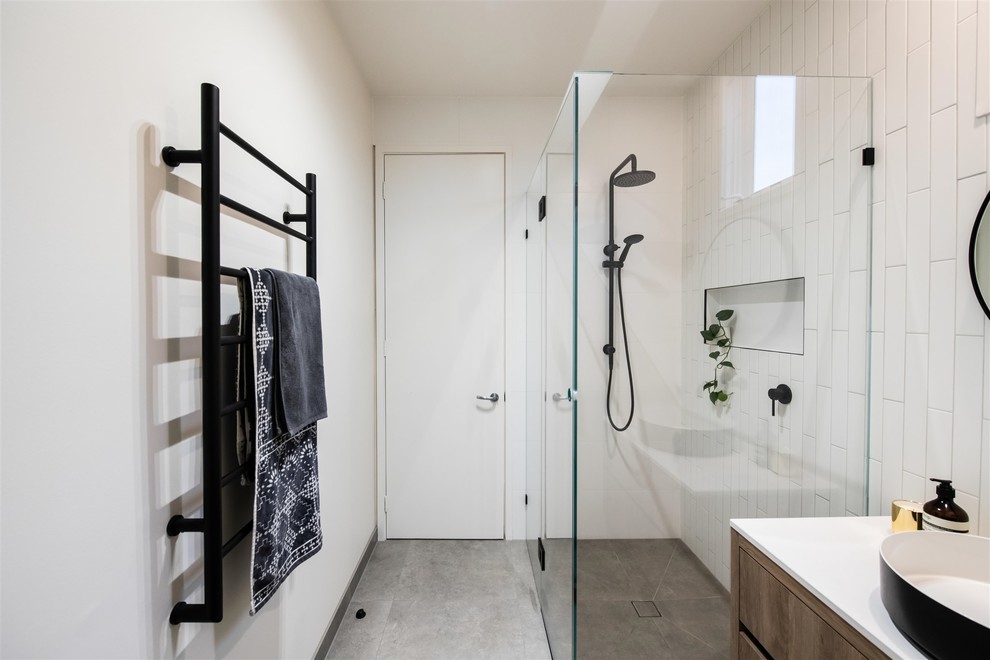 Design ideas for a medium sized contemporary ensuite bathroom in Melbourne with freestanding cabinets, light wood cabinets, a one-piece toilet, white tiles, ceramic tiles, white walls, porcelain flooring, a vessel sink, engineered stone worktops, grey floors and white worktops.