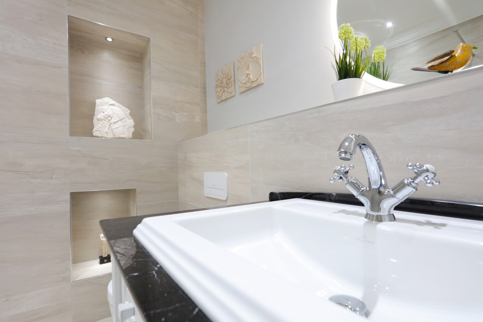 This is an example of a large classic family bathroom in Edinburgh with glass-front cabinets, white cabinets, a walk-in shower, a wall mounted toilet, beige tiles, porcelain tiles, beige walls, porcelain flooring, a submerged sink, beige floors, an open shower, a wall niche, a single sink, a freestanding vanity unit, marble worktops and black worktops.