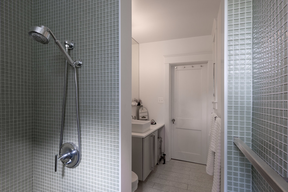 Пример оригинального дизайна: маленькая главная ванная комната в стиле модернизм с настольной раковиной, плоскими фасадами, столешницей из искусственного камня, душем в нише, унитазом-моноблоком, стеклянной плиткой и белыми стенами для на участке и в саду