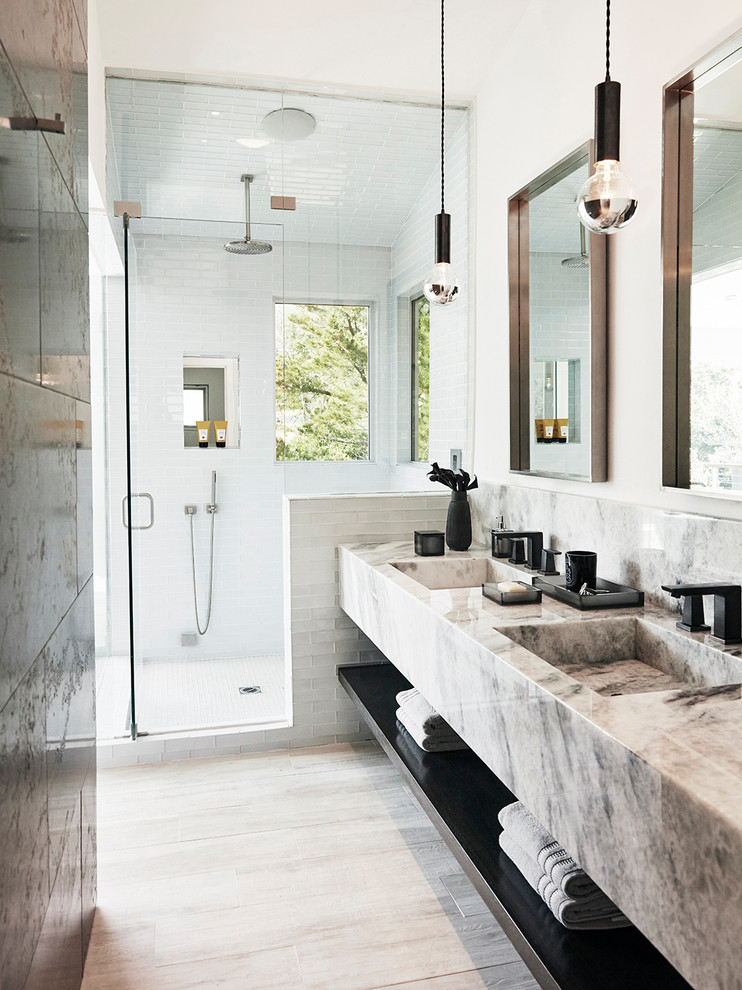 Bild på ett mellanstort funkis grå grått en-suite badrum, med öppna hyllor, vit kakel, tunnelbanekakel, vita väggar, ett integrerad handfat, dusch med gångjärnsdörr, vita skåp, en öppen dusch, ljust trägolv och marmorbänkskiva