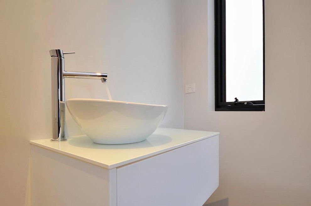Idee per una stanza da bagno minimal con lavabo integrato, ante lisce, vasca da incasso, WC sospeso, piastrelle grigie e pareti grigie
