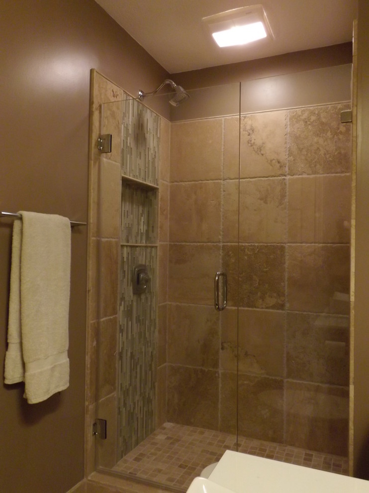 Photo of a small ensuite bathroom in Minneapolis with a vessel sink, flat-panel cabinets, grey cabinets, solid surface worktops, an alcove shower, a two-piece toilet, brown tiles, stone tiles, brown walls and travertine flooring.