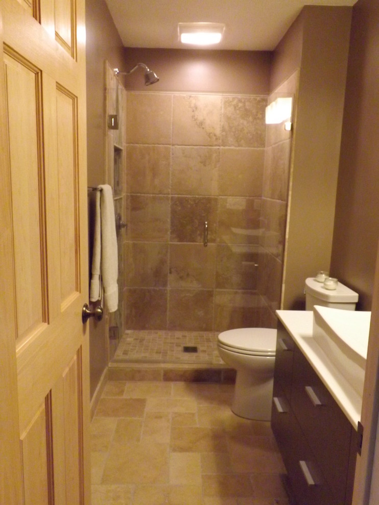 Small master brown tile and stone tile travertine floor alcove shower photo in Minneapolis with a vessel sink, flat-panel cabinets, gray cabinets, solid surface countertops, a two-piece toilet and brown walls