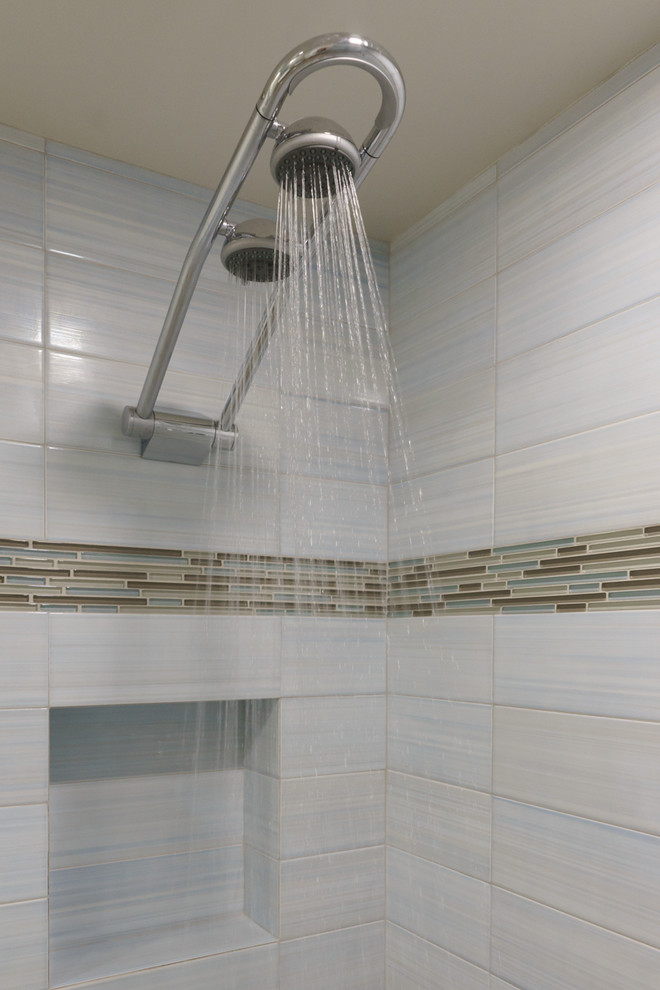 Photo of a small nautical shower room bathroom in Vancouver with a wall-mounted sink, flat-panel cabinets, white cabinets, a double shower, a wall mounted toilet, multi-coloured tiles, ceramic tiles, beige walls and pebble tile flooring.