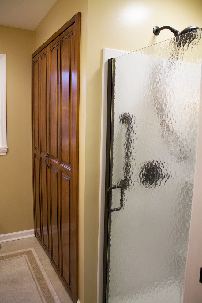 Idéer för små amerikanska badrum med dusch, med ett undermonterad handfat, möbel-liknande, skåp i mellenmörkt trä, marmorbänkskiva, en dusch i en alkov, en toalettstol med hel cisternkåpa, beige kakel, keramikplattor, bruna väggar och travertin golv