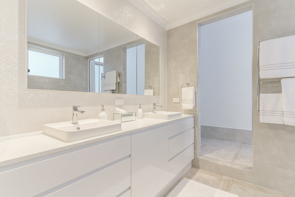 Cette photo montre une grande salle de bain principale moderne avec des portes de placard blanches, une baignoire indépendante, une douche d'angle, WC à poser, un carrelage beige, un mur beige, un sol en carrelage de céramique, un sol beige, une cabine de douche à porte battante et un plan de toilette blanc.