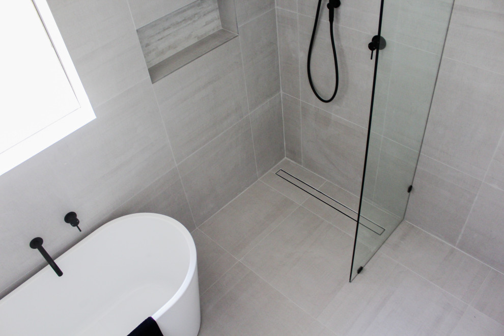 Photo of a medium sized modern ensuite wet room bathroom in Perth with flat-panel cabinets, white cabinets, a freestanding bath, a two-piece toilet, grey tiles, porcelain tiles, grey walls, porcelain flooring, a vessel sink, engineered stone worktops, grey floors, an open shower and grey worktops.