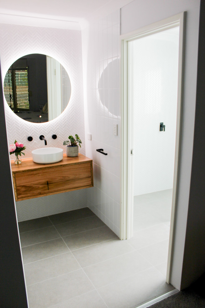 Inspiration för små moderna brunt badrum med dusch, med möbel-liknande, skåp i mörkt trä, en öppen dusch, en toalettstol med hel cisternkåpa, vit kakel, keramikplattor, vita väggar, klinkergolv i porslin, ett fristående handfat, träbänkskiva, grått golv och med dusch som är öppen
