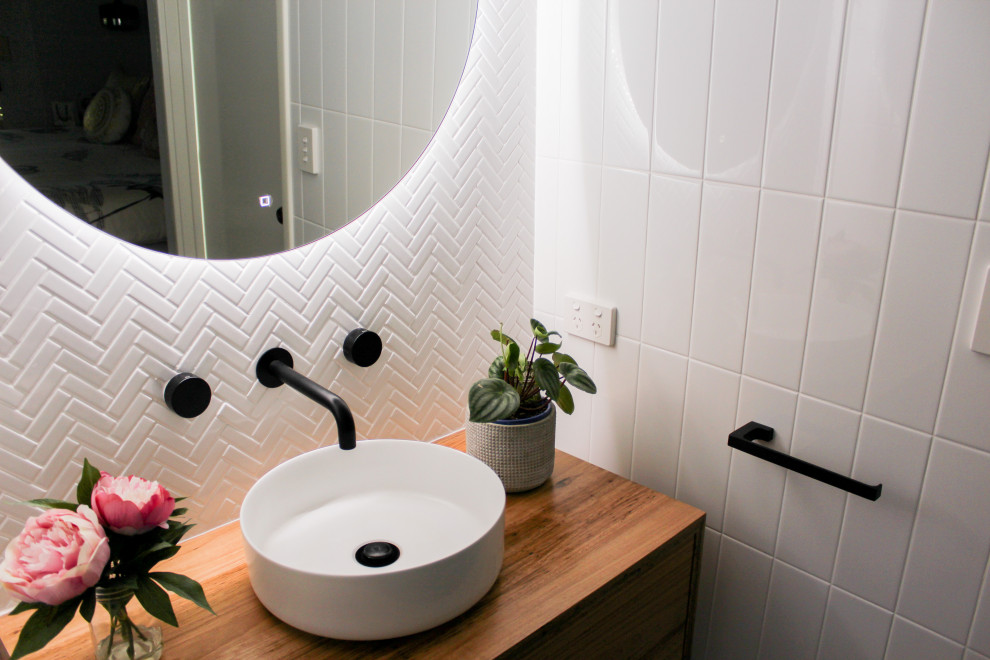 Modern inredning av ett litet brun brunt badrum med dusch, med möbel-liknande, skåp i mörkt trä, en öppen dusch, en toalettstol med hel cisternkåpa, vit kakel, keramikplattor, vita väggar, klinkergolv i porslin, ett fristående handfat, träbänkskiva, grått golv och med dusch som är öppen