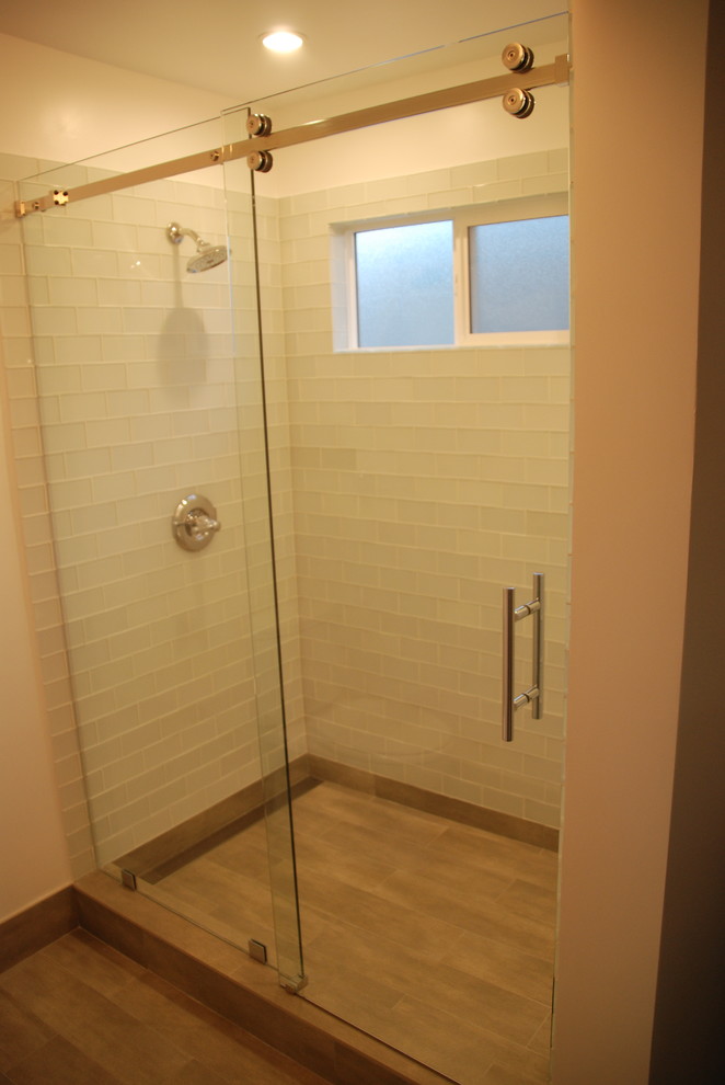 Medium sized contemporary shower room bathroom in Los Angeles with freestanding cabinets, grey cabinets, a walk-in shower, a two-piece toilet, white tiles, glass tiles, white walls, concrete flooring, a submerged sink, marble worktops, grey floors and a sliding door.