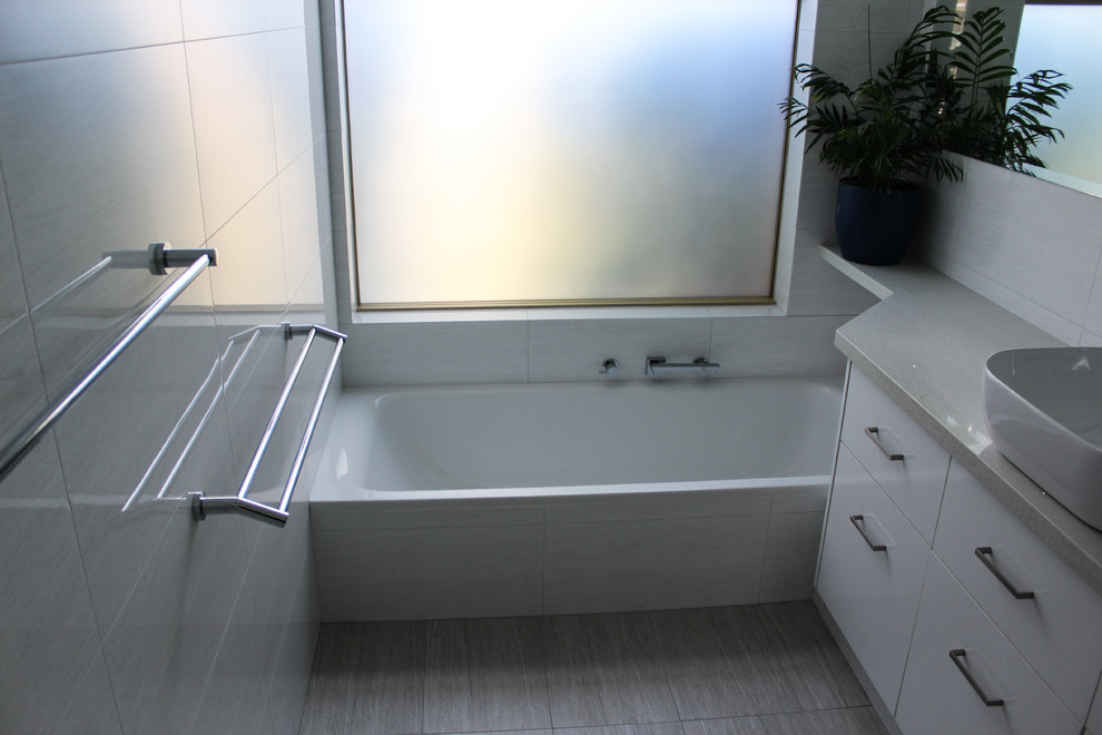 Inspiration för mellanstora moderna badrum med dusch, med luckor med infälld panel, vita skåp, ett platsbyggt badkar, en hörndusch, grå kakel, keramikplattor, grå väggar, klinkergolv i porslin, ett fristående handfat, bänkskiva i kvarts, grått golv och dusch med gångjärnsdörr