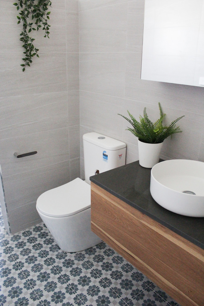 Example of a small minimalist 3/4 gray tile and porcelain tile ceramic tile and multicolored floor bathroom design in Perth with flat-panel cabinets, dark wood cabinets, a one-piece toilet, gray walls, a vessel sink, quartz countertops and black countertops
