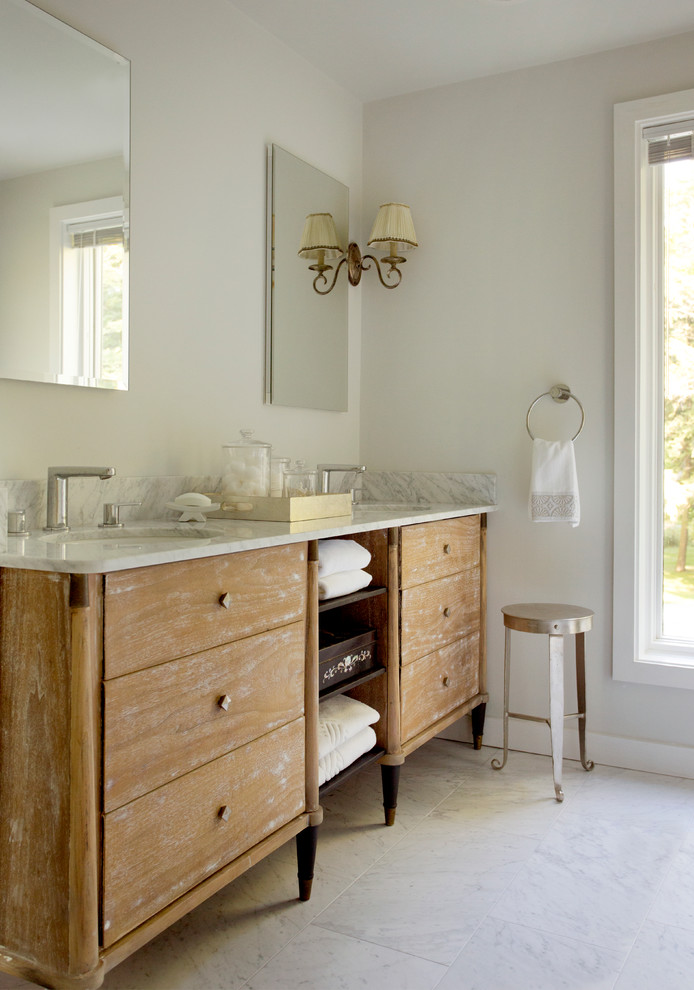 Cette image montre une salle de bain principale chalet en bois brun de taille moyenne avec un placard en trompe-l'oeil, un plan de toilette en marbre, une baignoire indépendante, un carrelage gris, un carrelage de pierre, un mur gris et un sol en marbre.