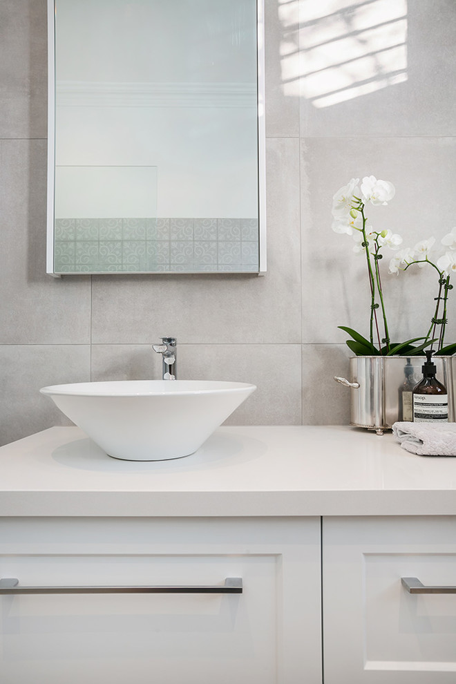 На фото: ванная комната в современном стиле с унитазом-моноблоком, белыми стенами, полом из керамогранита, настольной раковиной и столешницей из искусственного кварца