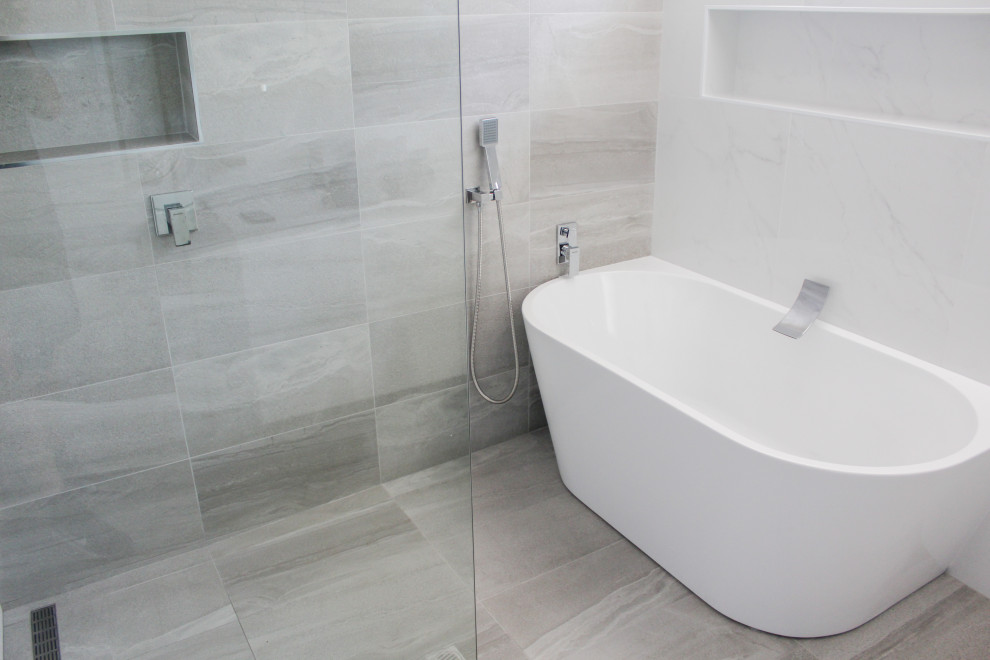 Idéer för ett stort vit badrum med dusch, med släta luckor, vita skåp, ett fristående badkar, våtrum, vit kakel, keramikplattor, vita väggar, klinkergolv i porslin, ett integrerad handfat, bänkskiva i akrylsten, grått golv och med dusch som är öppen