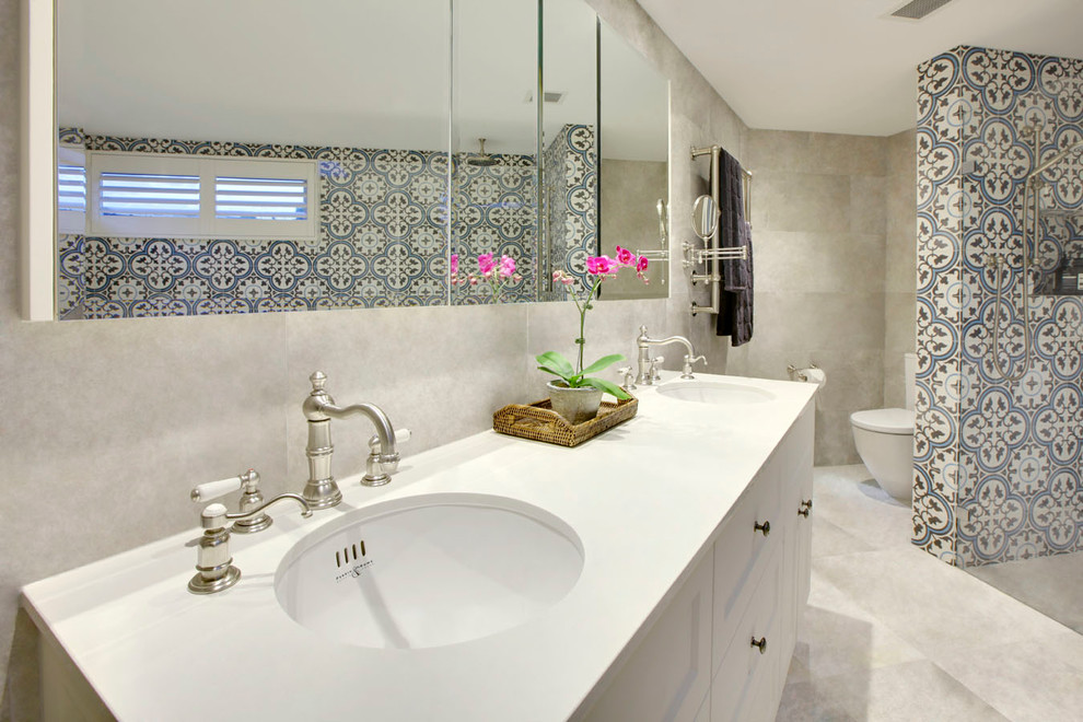 Diseño de cuarto de baño principal contemporáneo con armarios estilo shaker, puertas de armario blancas, sanitario de una pieza, paredes grises, suelo de travertino, lavabo encastrado y encimera de cuarzo compacto