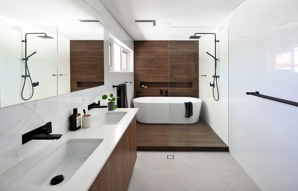 Immagine di una stanza da bagno minimal con ante lisce, ante in legno bruno, vasca freestanding, piastrelle marroni, lavabo sottopiano, pavimento grigio e top bianco