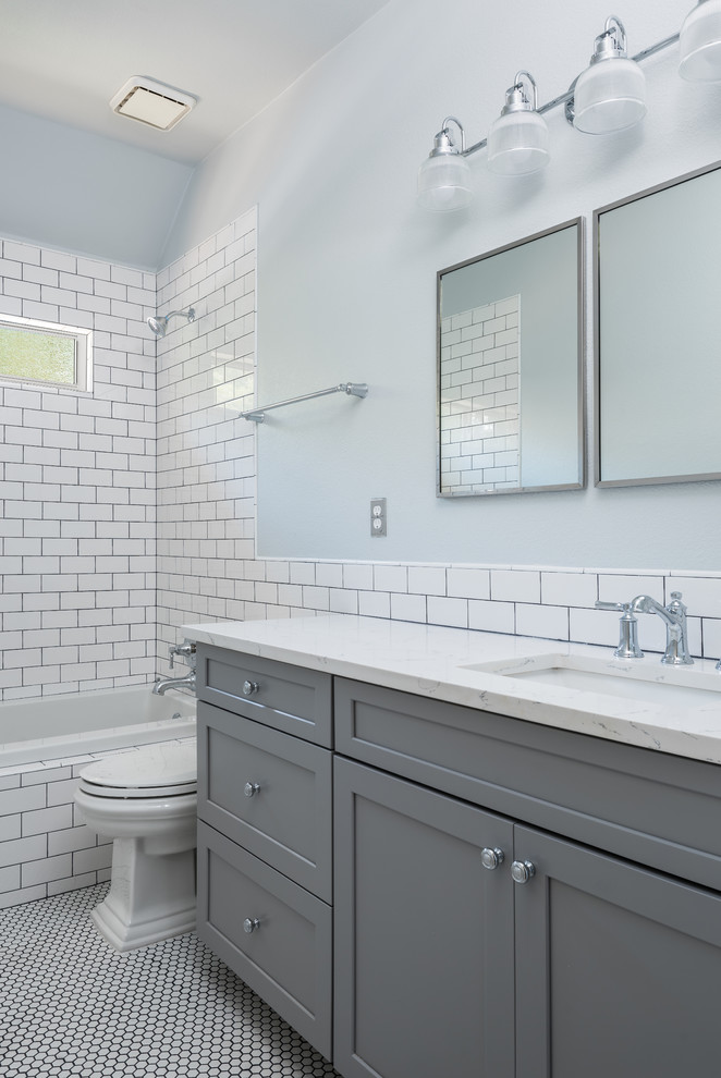 Idéer för att renovera ett litet funkis badrum med dusch, med luckor med infälld panel, grå skåp, ett badkar i en alkov, en dusch/badkar-kombination, en toalettstol med hel cisternkåpa, vit kakel, tunnelbanekakel, blå väggar, klinkergolv i småsten, ett integrerad handfat, marmorbänkskiva, vitt golv och med dusch som är öppen