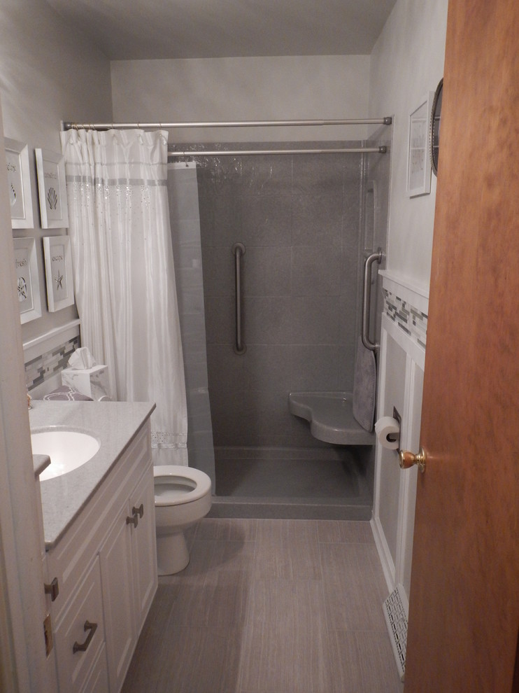 Bild på ett vintage badrum, med luckor med infälld panel, vita skåp, en öppen dusch, en toalettstol med hel cisternkåpa, grå kakel, porslinskakel, grå väggar, klinkergolv i porslin, ett undermonterad handfat och bänkskiva i onyx