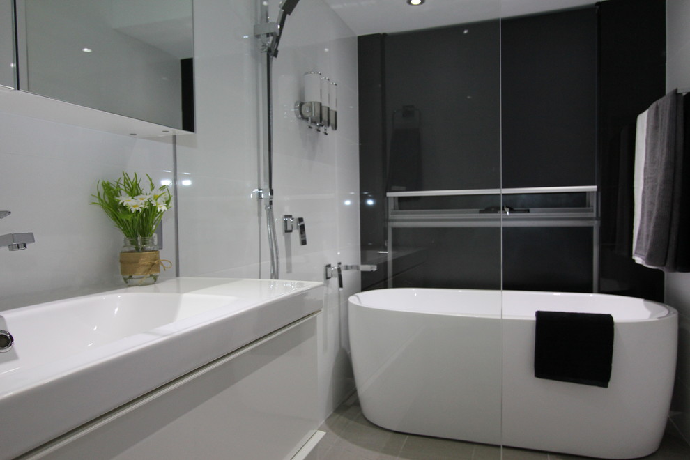 Cette photo montre une salle de bain moderne de taille moyenne pour enfant avec des portes de placard blanches, une baignoire indépendante, une douche ouverte, un mur blanc et un sol en carrelage de porcelaine.