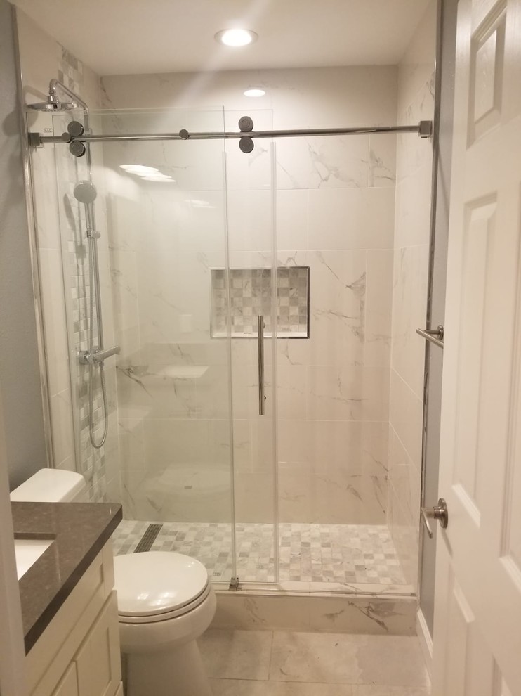 Klassisk inredning av ett litet brun brunt badrum med dusch, med skåp i shakerstil, vita skåp, en dusch i en alkov, en toalettstol med hel cisternkåpa, grå kakel, vit kakel, marmorkakel, grå väggar, ett undermonterad handfat, dusch med skjutdörr och grått golv