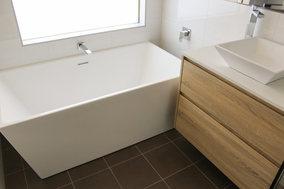 Idéer för att renovera ett mellanstort funkis badrum med dusch, med öppna hyllor, skåp i ljust trä, ett fristående badkar, en hörndusch, grå kakel, keramikplattor, grå väggar, klinkergolv i porslin, ett fristående handfat och bänkskiva i kvarts