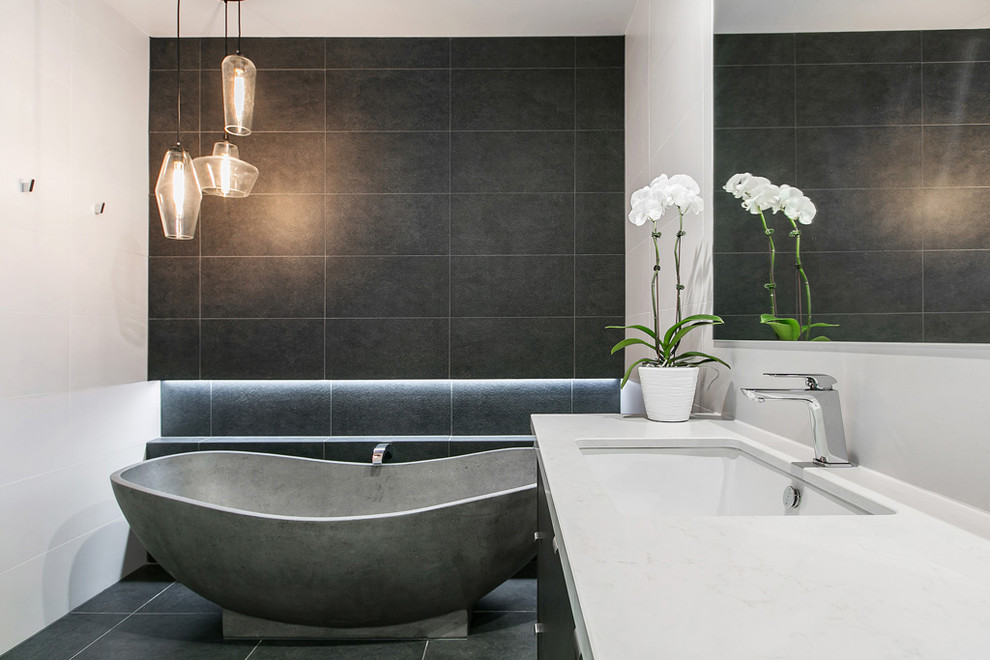 Пример оригинального дизайна: ванная комната в современном стиле с отдельно стоящей ванной, инсталляцией, белой плиткой, керамогранитной плиткой, белыми стенами, полом из керамогранита, накладной раковиной и столешницей из искусственного кварца