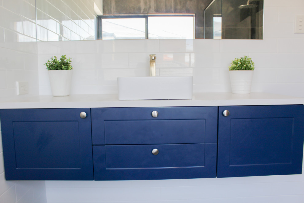 Inredning av ett modernt stort vit vitt en-suite badrum, med skåp i shakerstil, blå skåp, ett fristående badkar, en kantlös dusch, vit kakel, keramikplattor, flerfärgade väggar, ett fristående handfat, bänkskiva i kvarts, flerfärgat golv och dusch med gångjärnsdörr