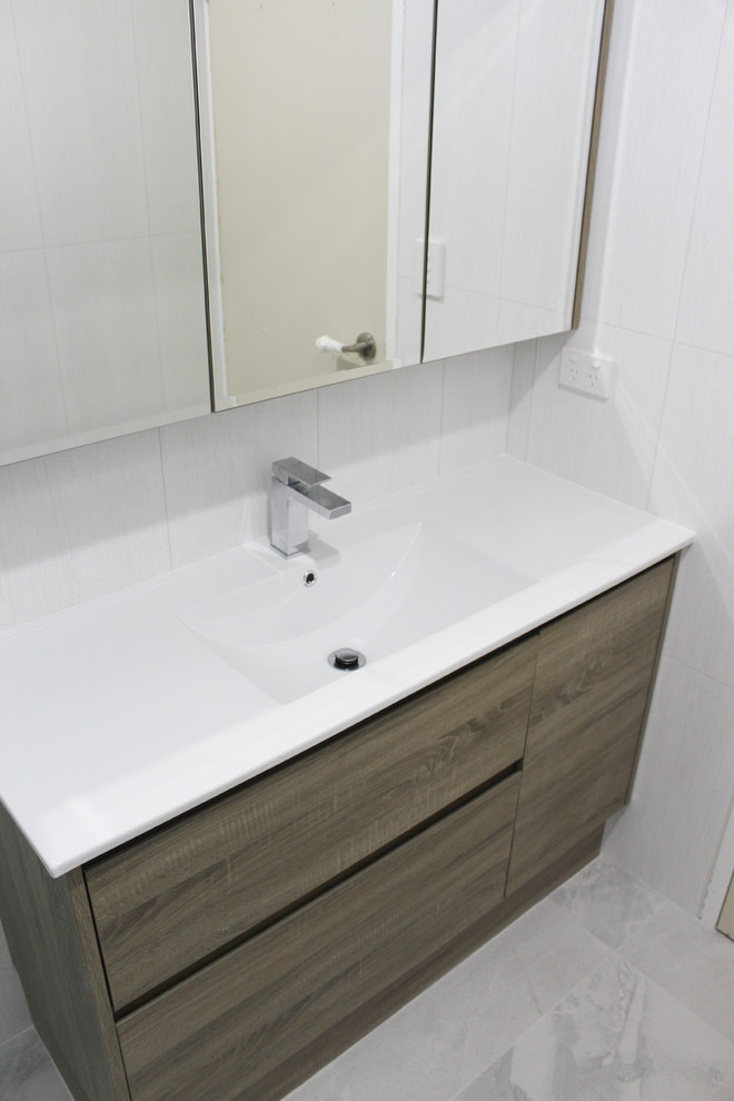 Exempel på ett litet vit vitt badrum med dusch, med släta luckor, skåp i mörkt trä, en öppen dusch, grå kakel, keramikplattor, grå väggar, klinkergolv i porslin, ett integrerad handfat, kaklad bänkskiva, vitt golv och med dusch som är öppen
