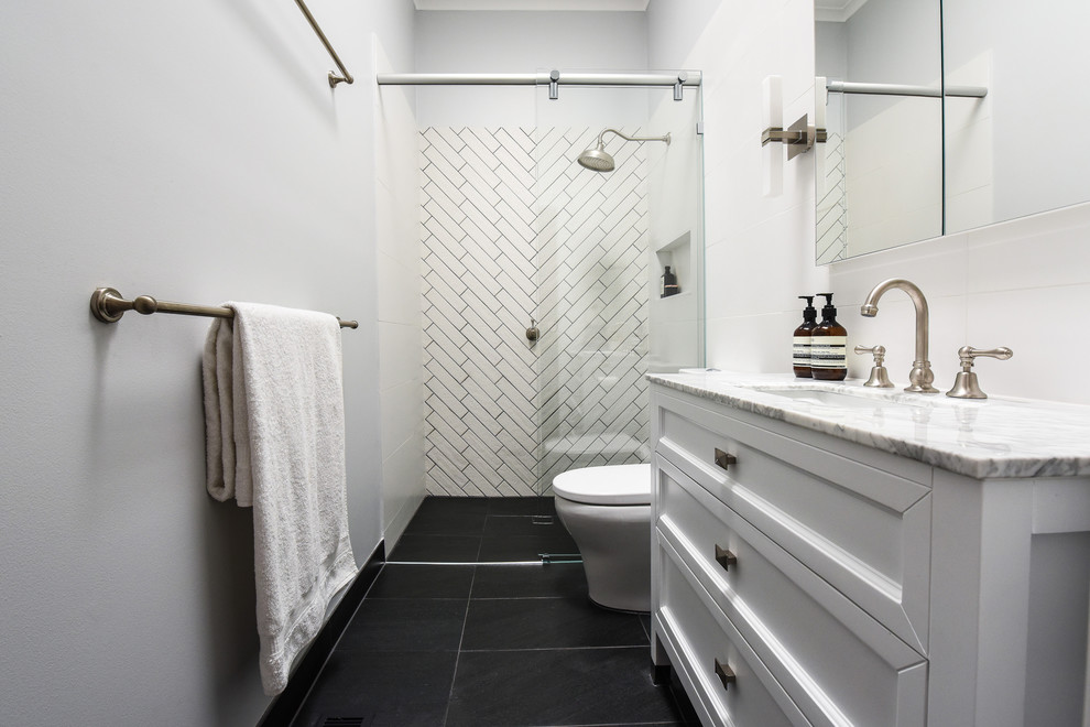Cette image montre une petite salle de bain principale traditionnelle avec un placard avec porte à panneau encastré, des portes de placard blanches, WC à poser, un carrelage blanc, des carreaux de céramique, un mur blanc, un sol en carrelage de porcelaine, un lavabo posé et un plan de toilette en marbre.