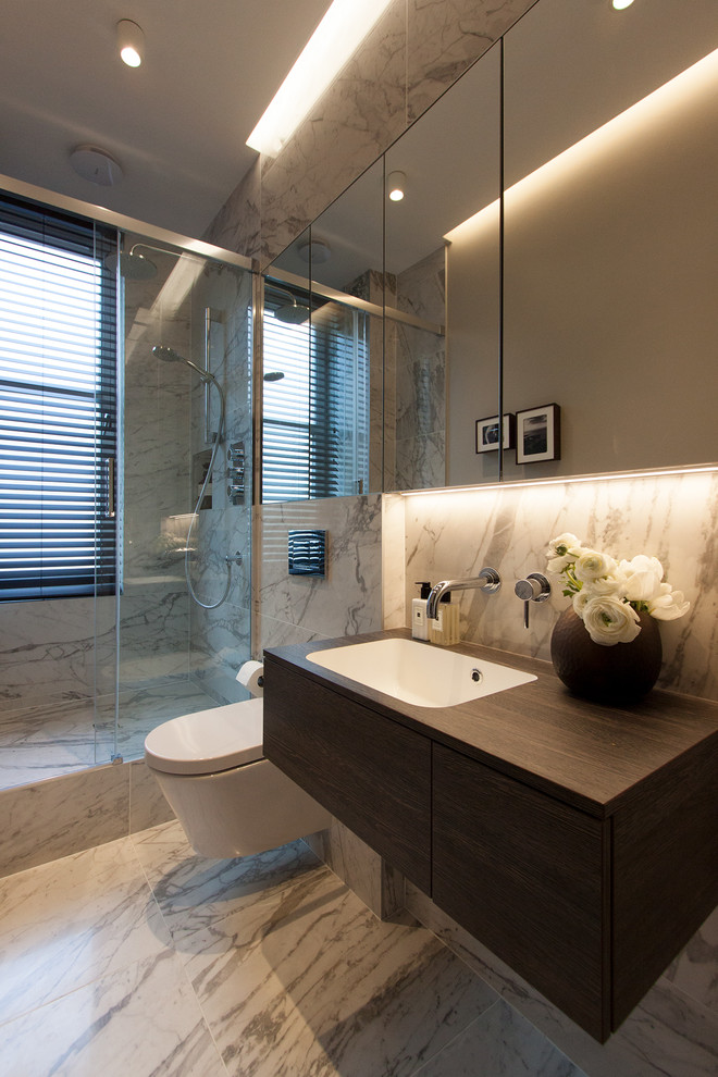 Bild på ett litet funkis badrum med dusch, med bruna skåp, en öppen dusch, en vägghängd toalettstol, vit kakel, marmorkakel, grå väggar, klinkergolv i porslin, ett väggmonterat handfat, laminatbänkskiva, vitt golv och dusch med skjutdörr