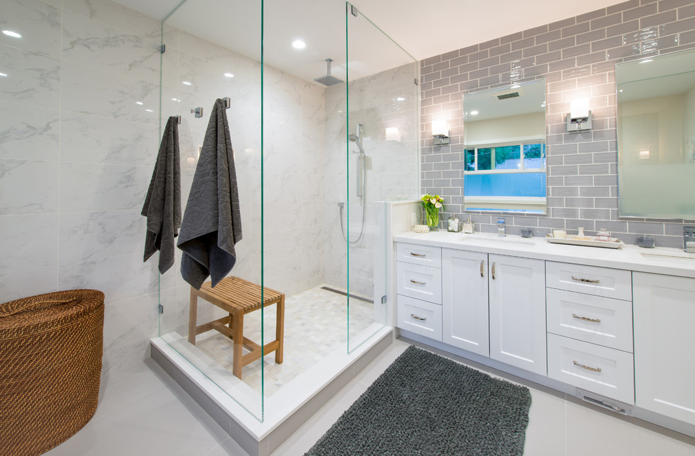 Inspiration for a large modern master white tile and porcelain tile porcelain tile and white floor doorless shower remodel in Vancouver with shaker cabinets, white cabinets, a two-piece toilet, gray walls, an undermount sink, quartz countertops and a hinged shower door