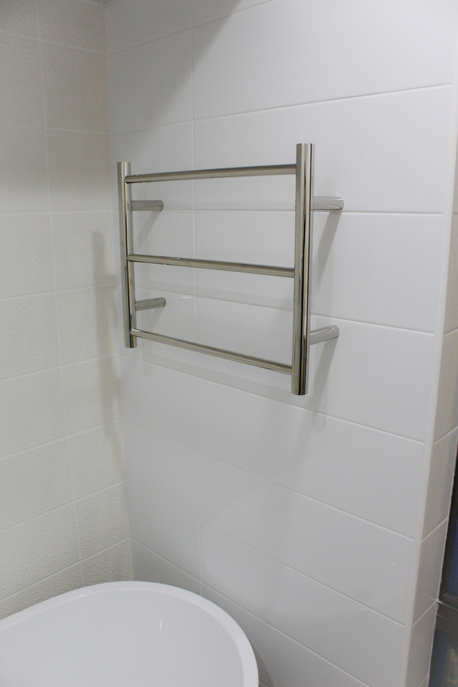 This is an example of a large modern shower room bathroom in Perth with recessed-panel cabinets, light wood cabinets, a freestanding bath, a walk-in shower, a one-piece toilet, white tiles, porcelain tiles, white walls, porcelain flooring, an integrated sink, solid surface worktops, brown floors and an open shower.