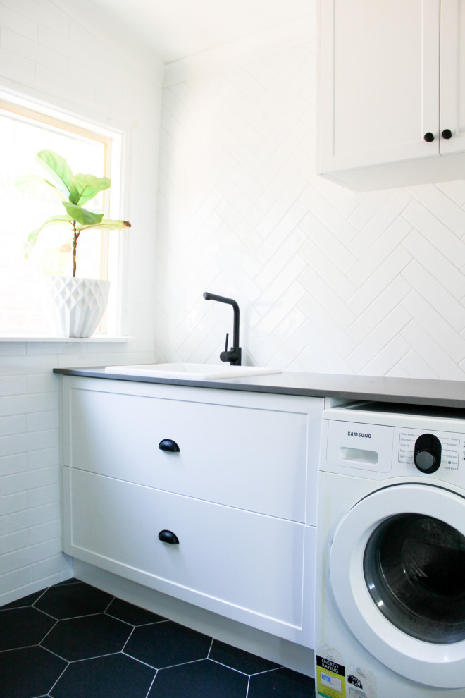 Modelo de lavadero minimalista grande con armarios estilo shaker, puertas de armario blancas, paredes blancas, suelo de baldosas de porcelana y suelo negro