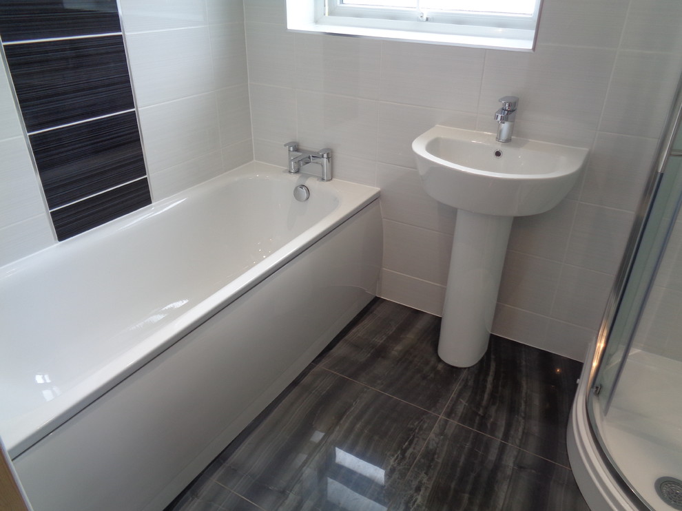 Exemple d'une salle de bain tendance pour enfant avec une douche d'angle, WC séparés, un carrelage blanc, des carreaux de céramique, un mur blanc, un sol en carrelage de porcelaine, un sol noir et une cabine de douche à porte coulissante.