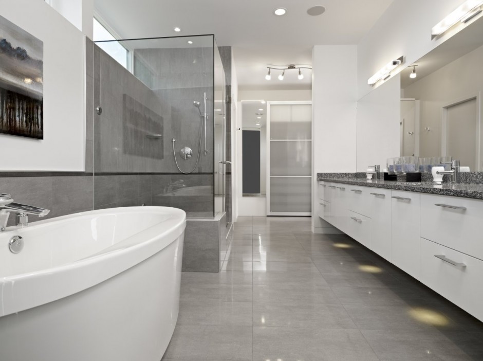 На фото: большая главная ванная комната в стиле модернизм с плоскими фасадами, белыми фасадами, столешницей из гранита, отдельно стоящей ванной, угловым душем, серой плиткой, керамогранитной плиткой, белыми стенами и полом из керамической плитки с