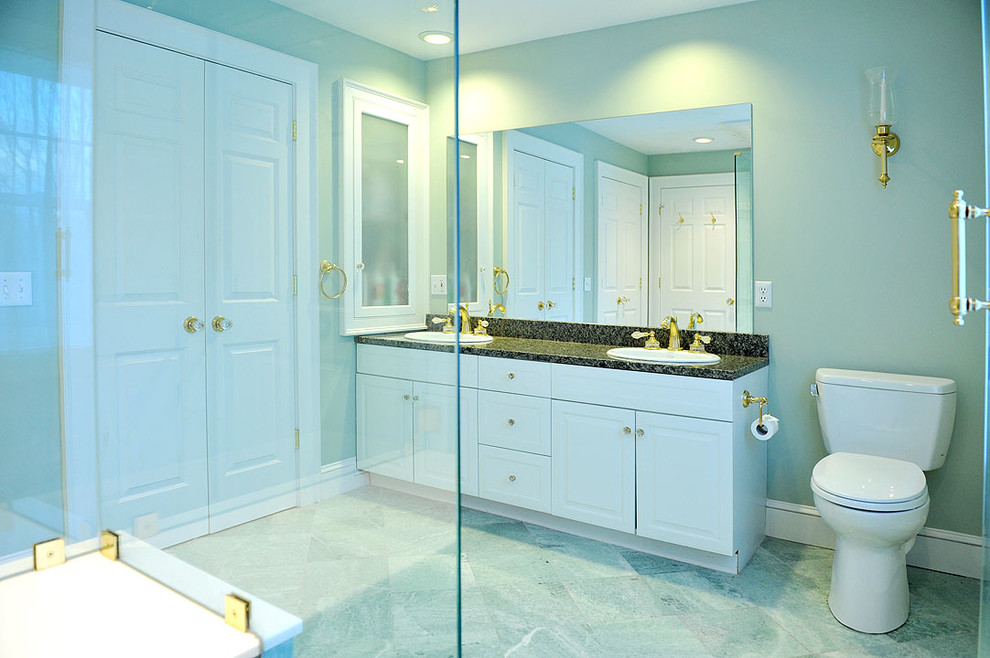Cette image montre une salle de bain design avec un lavabo posé, un placard avec porte à panneau surélevé, des portes de placard blanches, un plan de toilette en granite, une douche d'angle, WC séparés, un carrelage vert et un carrelage de pierre.