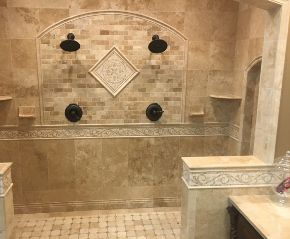 Идея дизайна: большая главная ванная комната в средиземноморском стиле с фасадами с выступающей филенкой, темными деревянными фасадами, двойным душем, бежевой плиткой, плиткой из травертина, бежевыми стенами, полом из травертина, настольной раковиной, столешницей из плитки, бежевым полом и открытым душем