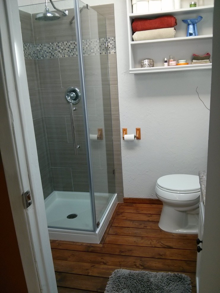 Example of a small mountain style master gray tile and ceramic tile medium tone wood floor and brown floor corner shower design in Other with recessed-panel cabinets, white cabinets, a two-piece toilet, white walls, a vessel sink, a hinged shower door and wood countertops