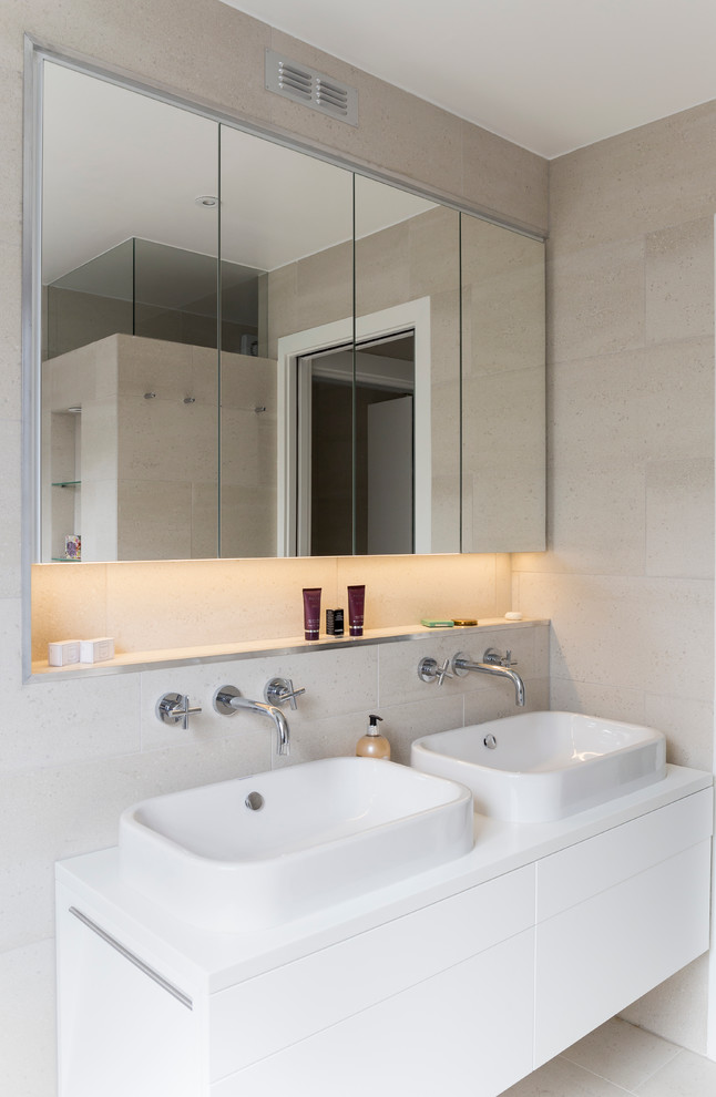 Inspiration for a small contemporary family bathroom in London with flat-panel cabinets, white cabinets, a built-in bath, a walk-in shower, a wall mounted toilet, beige tiles, porcelain tiles, beige walls, porcelain flooring, a built-in sink, quartz worktops, beige floors and a sliding door.