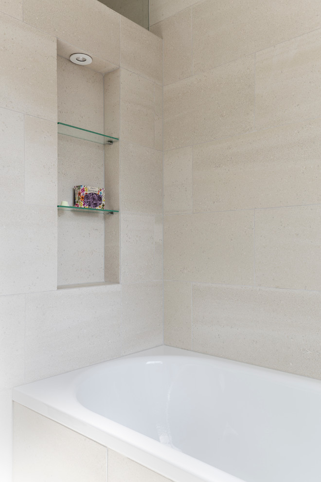Example of a small trendy kids' beige tile and porcelain tile porcelain tile and beige floor bathroom design in London with flat-panel cabinets, white cabinets, a wall-mount toilet, beige walls, a drop-in sink and quartzite countertops