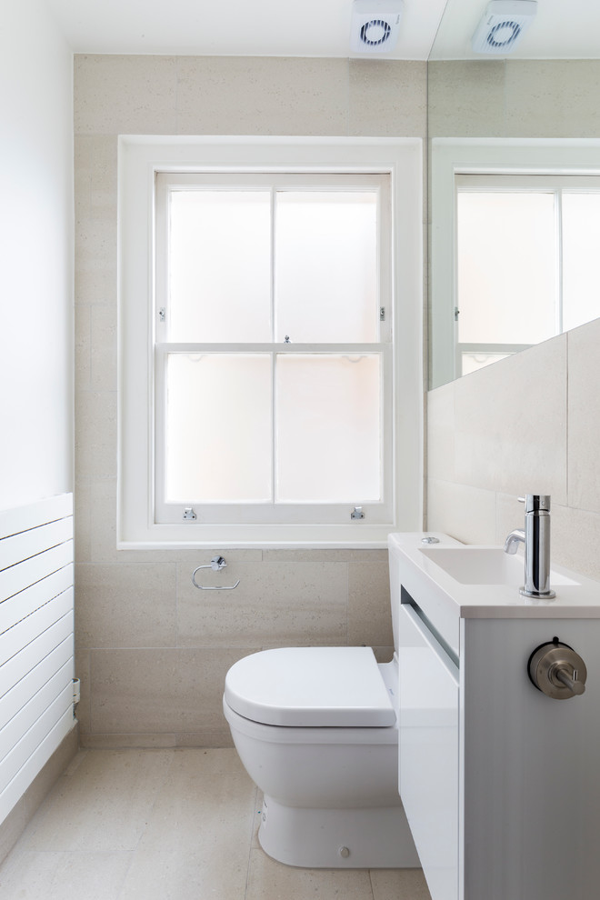 Inspiration for a small contemporary family bathroom in London with flat-panel cabinets, white cabinets, a built-in bath, a walk-in shower, a wall mounted toilet, beige tiles, porcelain tiles, beige walls, porcelain flooring, a built-in sink, quartz worktops, beige floors and a sliding door.