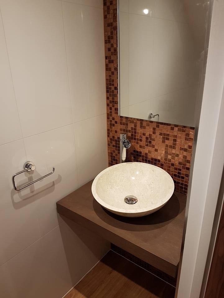 Cette photo montre une salle de bain moderne en bois foncé de taille moyenne pour enfant avec un placard avec porte à panneau surélevé, un carrelage marron, mosaïque, un mur multicolore, sol en stratifié, une vasque, un plan de toilette en zinc et un sol marron.