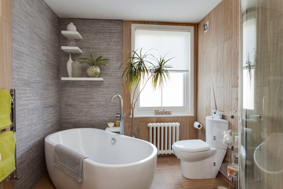 Immagine di una stanza da bagno padronale contemporanea con vasca freestanding, doccia ad angolo, WC a due pezzi, pareti grigie e pavimento in legno massello medio