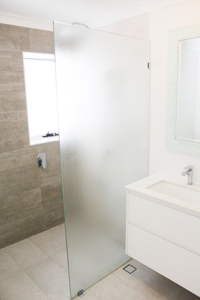 Foto på ett mellanstort funkis vit badrum med dusch, med släta luckor, vita skåp, en öppen dusch, en toalettstol med hel cisternkåpa, grå kakel, porslinskakel, vita väggar, klinkergolv i porslin, ett fristående handfat, bänkskiva i kvarts, grått golv och med dusch som är öppen