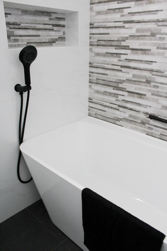 Inspiration for a large modern ensuite bathroom in Perth with flat-panel cabinets, grey cabinets, a freestanding bath, a corner shower, a one-piece toilet, white tiles, stone tiles, white walls, porcelain flooring, an integrated sink, solid surface worktops, black floors, a sliding door and white worktops.
