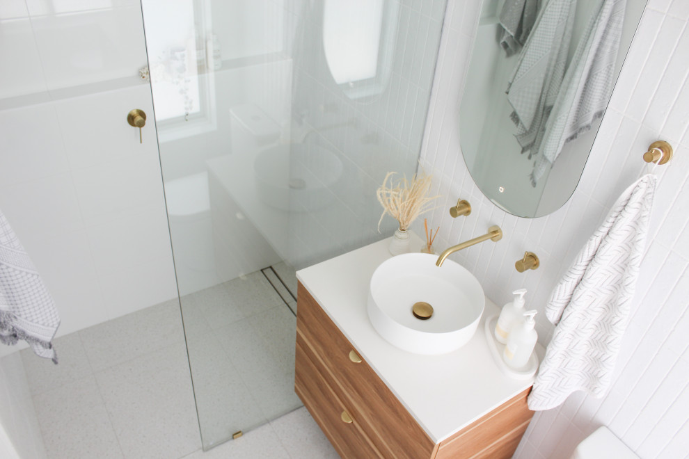 Пример оригинального дизайна: маленькая главная ванная комната в стиле модернизм с плоскими фасадами, темными деревянными фасадами, открытым душем, унитазом-моноблоком, белой плиткой, плиткой из сланца, белыми стенами, полом из керамогранита, настольной раковиной, столешницей из искусственного кварца, серым полом, открытым душем, белой столешницей, тумбой под одну раковину и подвесной тумбой для на участке и в саду