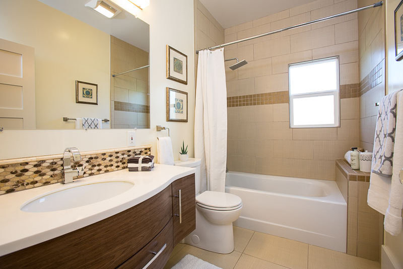 Bathroom - mid-sized contemporary beige tile and ceramic tile porcelain tile bathroom idea in San Francisco with a wall-mount sink, furniture-like cabinets, medium tone wood cabinets, solid surface countertops, a two-piece toilet and green walls